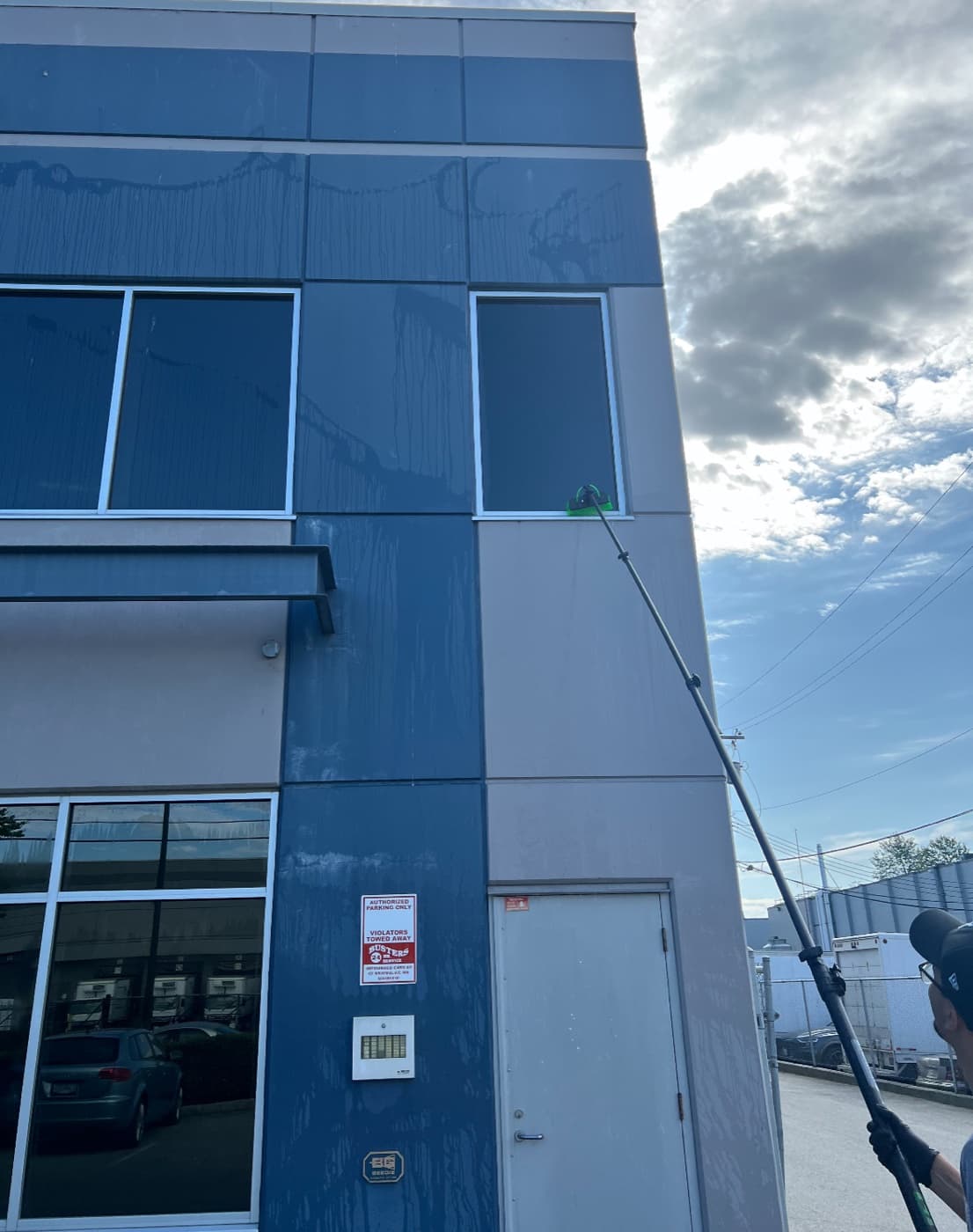 Axis Projects technician cleaning a commercial building's windows with a water-fed pole